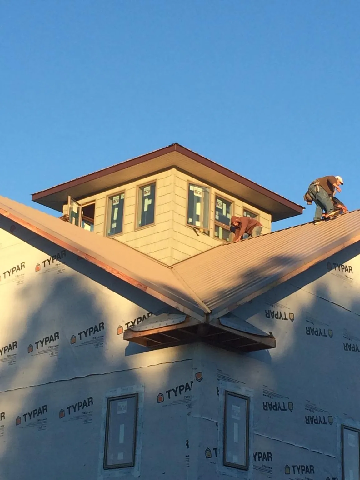 Roofers working around a rooftop cupola on a new metal roof at sunset — Roof Waterproofing in Yoder by Roofing Brothers